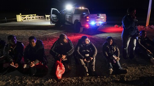 FILE - Migrants wait to be processed after crossing the border, Jan. 6, 2023, near Yuma, Ariz. A judge will hear arguments Wednesday, July 19, in a lawsuit opposing an asylum rule that has become a key part of the Biden administration’s immigration policy. Critics say the rule endangers migrants trying to cross the southern border and is against the law, while the administration argues that it encourages migrants to use lawful pathways into the country and prevents chaos at the border. (AP Photo/Gregory Bull, File)