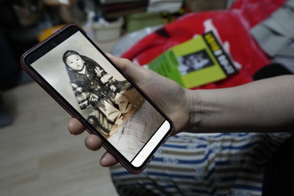 Choi Young-ja holds a smartphone displaying a photo of her son, who went missing in 1975, as she sits in her motel room in Seoul, South Korea, Tuesday, March 5, 2024. (AP Photo/Ahn Young-joon, File)