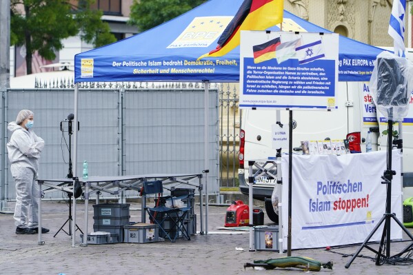 A forensic police officers walks past a smashed stall of Pax Europa which had a banner with writing reading "Stop political Islam", on the market square in Mannheim, Germany, Friday, May 31, 2024. An assailant with a knife attacked and wounded several people in a central square in the southwestern German city of Mannheim on Friday, police said. Police shot the attacker, who also was hurt. Pax Europa, which describes itself as an organization that informs the public about the dangers posed by the “increasing spread and influence of political Islam,” said that the attack happened on the sidelines of an event it organized. It said that Michael Stürzenberger, an anti-Islam activist who has spoken at its events. was among those wounded. (Uwe Anspach/dpa via AP)