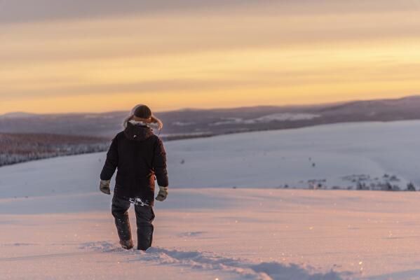 FILE - Reindeer herder Niila Inga from the Laevas Sami community walks across the snow as the sun sets on Longastunturi mountain near Kiruna, Sweden, on Nov. 27, 2019. A Swedish government-owned iron ore mining company says it has identified “significant deposits” of rare earth elements in Arctic Sweden that are essential for the manufacture of electric vehicles and wind turbines. LKAB's CEO said the quantity of rare earth metals exceeds 1 million tons and is the largest known deposit of its kind in Europe. Sweden's Energy and Business Minister said "the EU’s self-sufficiency and independence from Russia and China will begin in the mine.” (AP Photo/Malin Moberg)