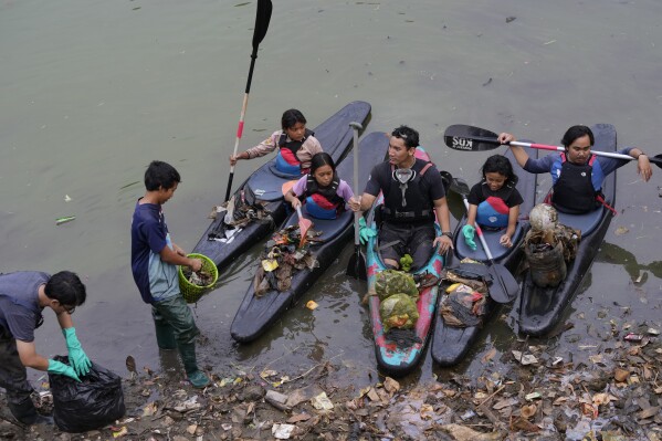Environmental activist members of the Situ Gede Cleanliness Warrior pick up trash while paddling kayaks at Setu Gede lake in Bogor, West Java, Indonesia, Tuesday, Oct. 10, 2023. Young people have been at the forefront of environmental and climate change movements in recent years: initiatives like school strikes for climate action, protests at United Nations climate talks and around the world, and local clean ups have often been youth-led. (AP Photo/Achmad Ibrahim)