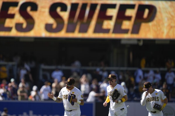 San Diego Padres right fielder David Peralta, left, celebrates with teammates center fielder Jackson Merrill and left fielder Bryce Johnson after the Padres defeated the Pittsburgh Pirates 8-2 in a baseball game to sweep the series, Wednesday, Aug. 14, 2024, in San Diego. (AP Photo/Gregory Bull)