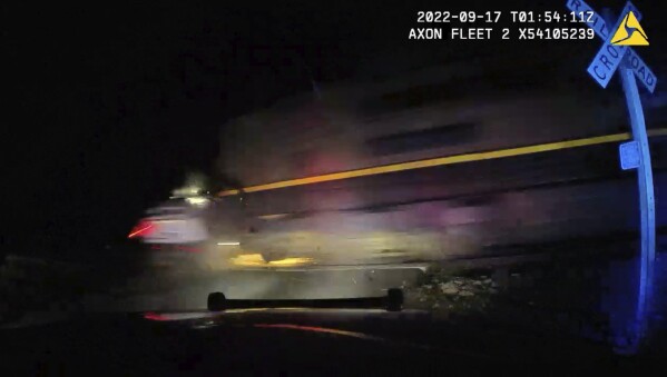 This screen grab from dash camera video provided by the Fort Lupton Police Department shows a freight train hitting a parked police car with a suspect inside, Sept. 16, 2022, in Fort Lupton, Colo. A trial began Monday, July 24, 2023, for the police officer accused of putting the handcuffed woman in the car. The collision seriously injured 21-year-old Yareni Rios. The date/time stamp shown on the video is incorrect. (Fort Lupton Police Department via AP)