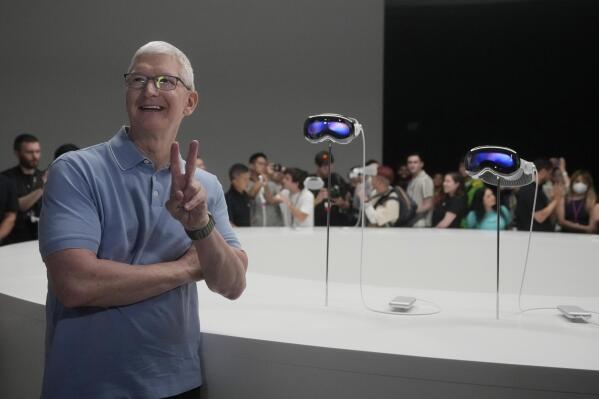 Apple CEO Tim Cook poses for photos in front of the company's new Apple Vision Pro headsets in a showroom on the Apple campus Monday, June 5, 2023, in Cupertino, Calif. (AP Photo/Jeff Chiu)