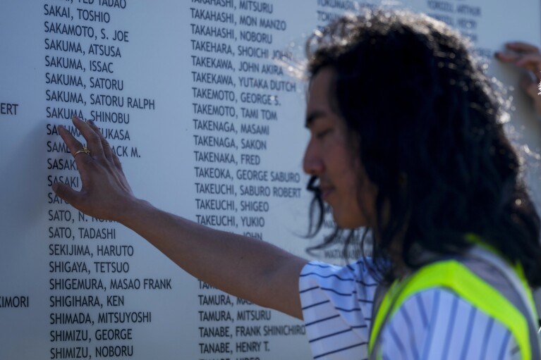 Jonnie Narita places a hand on the honor roll at the entrance of the Minidoka National Historic Site during a tour Saturday, July 8, 2023, in Jerome, Idaho. (AP Photo/Lindsey Wasson)
