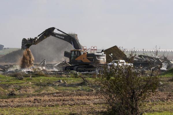 An Israeli excavator demolishes the remains of Karni commercial border crossing between Israel and Gaza Strip, east of Gaza City, Tuesday, Dec. 6, 2022. Israeli bulldozers and cranes were seen Tuesday dismantling a commercial crossing point on the eastern side of Gaza City as Israel decided to extend a security barrier at the location of the long-defunct terminal. (AP Photo/Adel Hana)