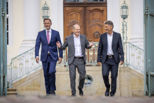 German Chancellor Olaf Scholz, center, German Economy and Climate Minister Robert Habeck, right, and German Finance Minister Christian Lindner, left, arrive for a press conference during a closed cabinet meeting at the government's guesthouse Meseberg in Gransee, north of Berlin, Germany, Wednesday, Aug. 30, 2023. (Michael Kappeler/dpa via AP)
