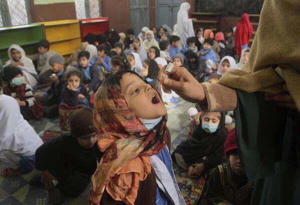 A health worker administers a polio vaccine to a child at a school, in Peshawar, Pakistan, Monday, Feb. 28, 2022. (AP Photo/Muhammad Sajjad)