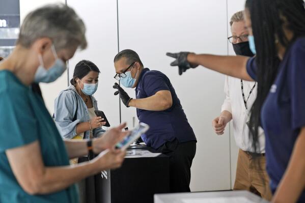 FILE — Staff at the Modern Museum of Art check visitors' proof of vaccination in New York, Sept. 13, 2021. New York City's health commissioner said Monday he is "strongly recommending" that everyone wear masks in indoor public settings as scientists work to learn more about the newly identified omicron variant of COVID-19. (AP Photo/Seth Wenig, File)