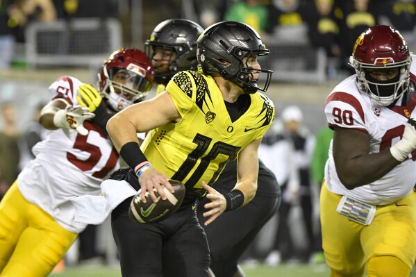 Oregon quarterback Bo Nix (10) scrambles as he is pursued by Southern California defensive end Solomon Byrd (51) and defensive lineman Bear Alexander (90) during the first half of an NCAA college football game Saturday, Nov. 11, 2023, in Eugene, Ore. (AP Photo/Andy Nelson)