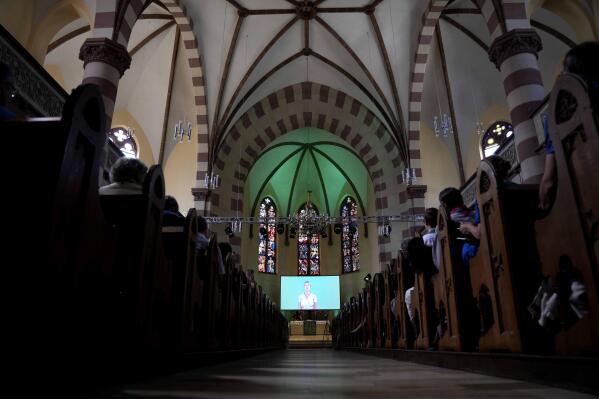 People attend a church service in Nuremberg, Germany, Friday, June 9, 2023. Hundreds of German Protestants have attended a church service in Bavaria that was generated almost entirely by artificial intelligence. The service was created by ChatGPT and Jonas Simmerlein, a theologian and philosopher from the University of Vienna. The ChatGPT chatbot, personified by different avatars on a huge screen above the altar, led the more than 300 people through 40 minutes of prayer, music, sermons and blessings. (APPhoto/Matthias Schrader)