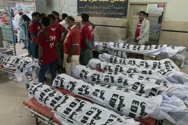 Volunteers gather beside the bodies of the victims of a bus crash, at a morgue in Karachi, Pakistan, Thursday, April 11, 2024. A Pakistani official says a bus crash has killed and injured multiple persons in the country's southwest. (AP Photo/M. Farooq)