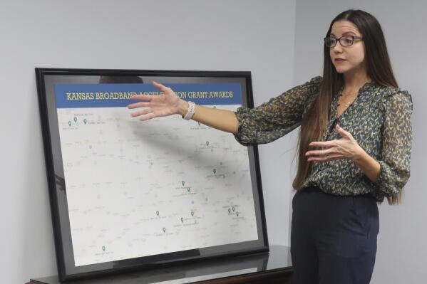 Jade Piros de Carvalho, director of the Office of Broadband Development in the Kansas Department of Commerce, talks about the need for broadband internet service across the state with a map of state grants for projects, Wednesday Dec. 13, 2022, in the department's offices in Topeka, Kansas. States are facing a tight deadline for proposing corrections to the federal government map that spells out which areas lack broadband service. (AP Photo/John Hanna)