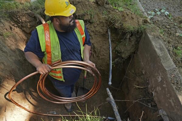 FILE - A worker with Denver Water prepares to pass a new copper water service line from a residential water meter to the water main June 17, 2021, in Denver. The Environmental Protection Agency on Thursday, Dec. 1, 2022, approved a nearly $700 million plan to remove all lead water pipes in the Denver region. (AP Photo/Brittany Peterson, File)