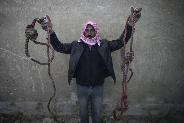 A man holds two ropes tied in the shape of nooses, found in the infamous Saydnaya military prison, just north of Damascus, Syria, Monday, Dec. 9, 2024. (AP Photo/Hussein Malla, File)