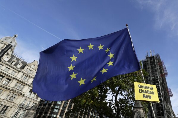 An anti-Brexit demonstrator holds up a banner attached to a European Union flag outside Parliament in London, Wednesday, Oct. 30, 2019. Britons will be heading out to vote in the dark days of December after the House of Commons on Tuesday backed an early national vote that could break the country's political impasse over Brexit — or turn out to be merely a temporary distraction. (AP Photo/Kirsty Wigglesworth)