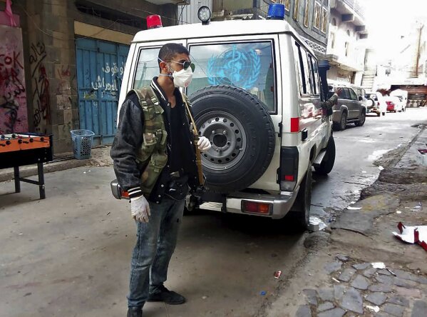 This May 2020 photo provided by a Yemeni Community activist, shows an activist waiting for an ambulance to collect the body of a COVID-19 victim, after medics declined to take the body, in the Houthi-controlled city of Ibb, Yemen. An investigation by The Associated Press found that the coronavirus is taking a deadly toll on the war weary population of Yemen. The situation is exacerbated in the Houthi-controlled north where the rebels have suppressed information about the virus, severely punished those who speak out, enforced little mitigation measures, and promoted conspiracies and claims by the Houthi minister of health that scientists are working on developing a cure for covid-19 to present to the world. (Courtesy of a Yemeni Community Activist via AP)