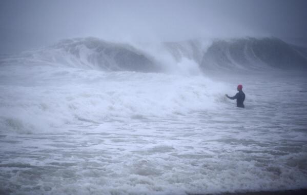 Matt Prue, from Stonington, Conn., walks out into the Atlantic Ocean to body surf the waves from Tropical Storm Henri as it approaches Westerly, R.I., Sunday, Aug. 22, 2021. (AP Photo/Stew Milne)