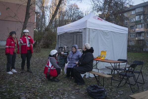 Paramedics give psychological aid to residents of a damaged apartment building following a Russian drone attack in Kyiv, Ukraine, Saturday, Nov. 25, 2023. Russia launched its most intense drone attack on Ukraine since the beginning of its full-scale invasion on Saturday morning, military officials said. (AP Photo/Efrem Lukatsky)