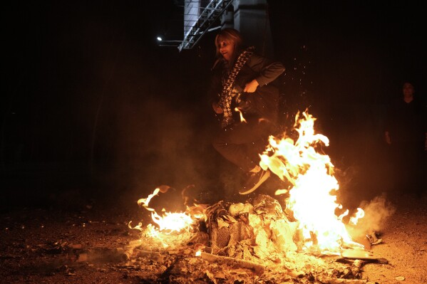 An Iranian woman jumps over a bonfire celebrating Chaharshanbe Souri, or Wednesday Feast, an ancient Festival of Fire on the eve of the last Wednesday of the Persian year, in Tehran, Iran, Tuesday, March 18, 2025. (AP Photo/Vahid Salemi)