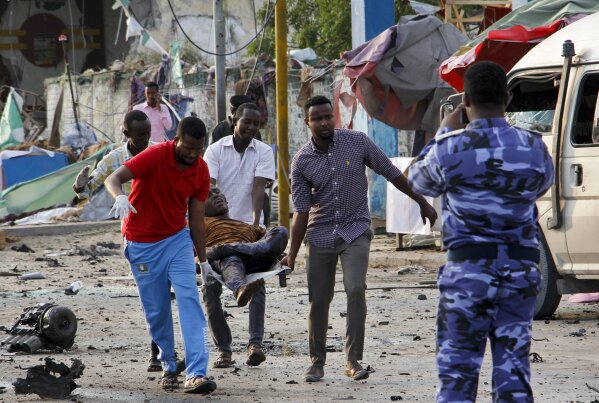 
              Somalis carry away an injured civilian who was wounded in a bomb blast near the Sahafi hotel in the capital Mogadishu, Somalia Friday, Nov. 9, 2018. Three car bombs by Islamic extremists exploded outside the hotel, which is located across the street from the police Criminal Investigations Department, killing at least 10 people according to police. (AP Photo/Farah Abdi Warsameh)
            