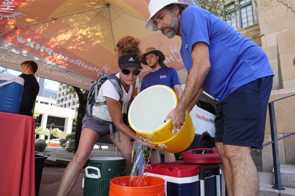 FILE - The City of Phoenix Heat Response Program team volunteers Natalie Boyd, left, and David Coughenour, right, prepare heat relief kits for the public in need July 20, 2023, in Phoenix. July has been so hot so far that scientists calculate that this month will be the hottest globally on record and likely the warmest human civilization has seen, even though there are several days left to sweat. (AP Photo/Ross D. Franklin, File)