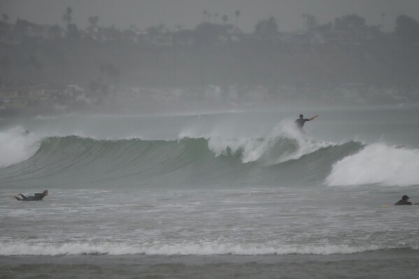 Surfers ride waves off Doheny State Park Beach in Dana Point, Calif., Sunday, Aug. 20, 2023. Tropical Storm Hilary swirled northward Sunday just off the coast of Mexico's Baja California peninsula, no longer a hurricane but still carrying so much rain that forecasters said "catastrophic and life-threatening" flooding is likely across a broad region of the southwestern U.S. (AP Photo/Damian Dovarganes)