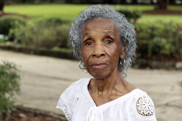 Josephine Wright poses in her yard facing a barren plot under development in Hilton Head Island, S.C., June 2023. Wright, who drew national attention from the likes of Tyler Perry and Snoop Dogg as she fought off developers in her final years, died Sunday, Jan. 7, 2024, at her Hilton Head home surrounded by loved ones, according to a publicist for her family. She was 94. (AP Photo/James Pollard)