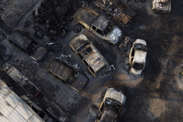 Charred vehicles sit at an auto body shop after the property was burned by the Smokehouse Creek Fire, Wednesday, Feb. 28, 2024, in Canadian, Texas. (AP Photo/Julio Cortez)