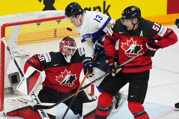 Canada's goalkeeper Jordan Binnington, left, and Canada's Colton Parayko, right, make a save against Finland's Jesse Puljujarvi during the preliminary round match between Canada and Finland at the Ice Hockey World Championships in Prague, Czech Republic, Saturday, May 18, 2024. (AP Photo/Petr David Josek)