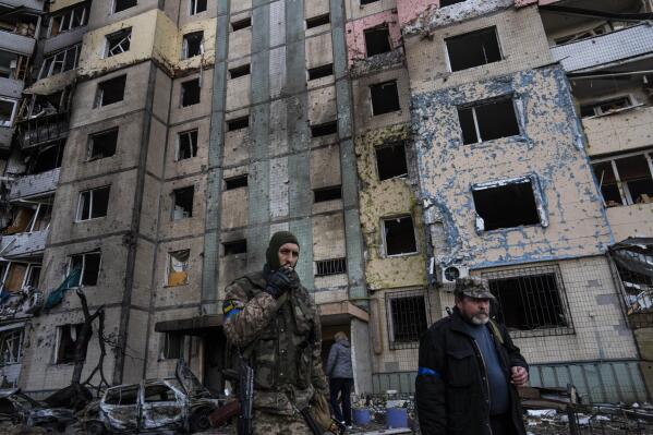 A soldier smokes a cigarette while walking next to a destroyed building after a bombing in Satoya neighborhood in Kyiv, Ukraine, Sunday, March 20, 2022. (AP Photo/Rodrigo Abd)