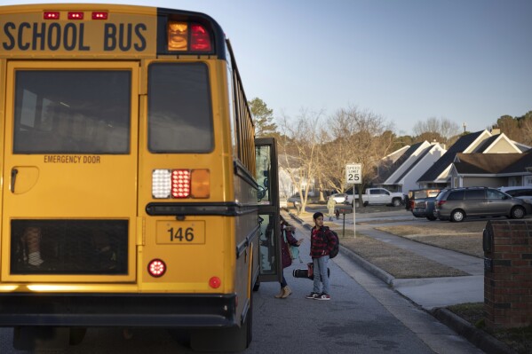 CORRECTS NAME TO GABE AYALA FROM LIAM LAZO - Gabe Ayala boards a diesel school bus near his home, Tuesday, Feb. 6, 2024, in Virginia Beach, Va. Diesel exhaust from school buses affects one-third of U.S. students, their parents and educators each day. (AP Photo/Tom Brenner)