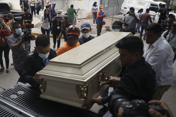 People place a coffin containing the remains of a female inmate into a hearse in Tegucigalpa, Honduras, Wednesday, June 21, 2023. A riot on Tuesday at a women's prison northwest of the Honduran capital left at least 46 inmates dead, many of them burned, shot or stabbed to death, a Honduran police official said. (AP Photo/Elmer Martinez)