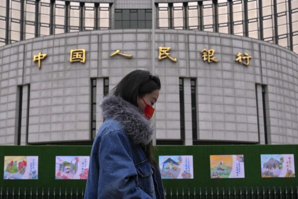 A woman walks by China's central bank, or the People's Bank of China in Beijing, Tuesday, Feb. 20, 2024. China's central bank announced it cut its five-year loan prime rate while leaving its one-year rate unchanged. (AP Photo/Andy Wong)