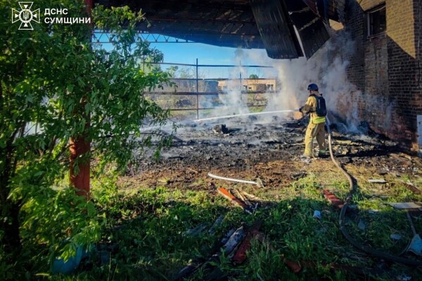 In this photo provided by the Ukrainian Emergency Services on May 8, 2025, a rescue worker puts out a fire of a building which was heavily damaged by a Russian strike in Sumy region, Ukraine. (Ukrainian Emergency Service via AP)