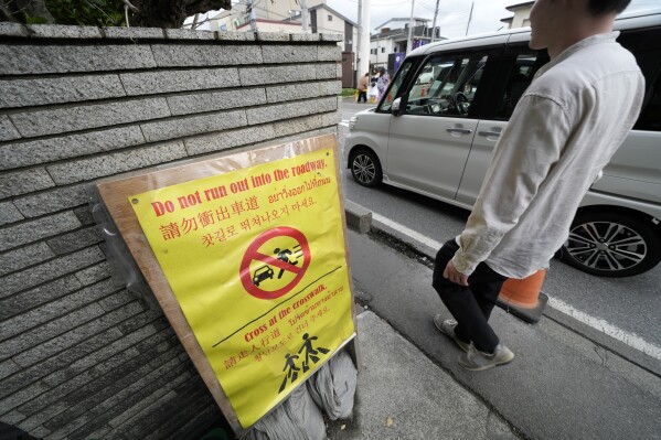 Hinweis für Touristen über den Nutzungspfad des Lawson Convenience Store, wo am Dienstag, dem 30. April 2024, in Fujikawaguchiko, Präfektur Yamanashi, Zentraljapan, ein beliebter Fotopunkt einen malerischen Blick auf den Berg Fuji im Hintergrund einrahmt.  (AP Photo/Eugene Hoshiko)