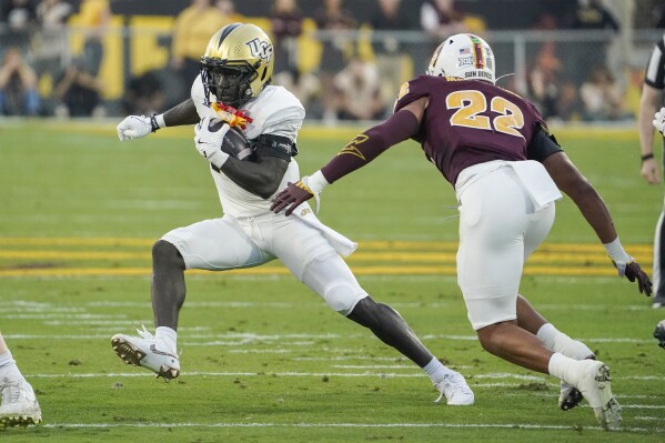 Central Florida running back Myles Montgomery, left, finds running room against Arizona State linebacker Caleb McCullough (22) during the first half of an NCAA college football game Saturday, Nov. 9, 2024, in Tempe, Ariz. (AP Photo/Darryl Webb, File)
