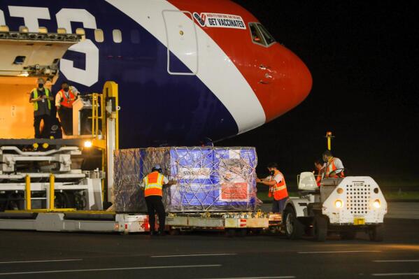 In this photo provided by El Salvador's presidential press office, airport workers unload a container of Chinese-made Sinovac COVID-19 vaccines from The New England Patriots team plane at the airport in San Salvador, El Salvador, late Tuesday, May 18, 2021. (El Salvador's presidential press office via AP)