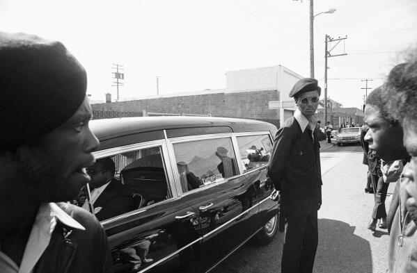FILE - Black Panthers stand guard on Aug. 28, 1971, in Oakland, Calif., while the hearse carrying the body of George Jackson was brought to St. Augustine's Episcopal Church. First celebrated in 1979, Black August was originally created to commemorate Jackson's fight for Black liberation. Fifty one years since his death, Black August is now a month-long awareness campaign and celebration dedicated to Black American freedom fighters, revolutionaries, radicals and political prisoners, both living and deceased. (APPhoto/Robert Klein, File)