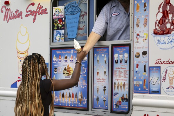A woman buys an ice cream cone during National Night Out, Tuesday, August 1, 2023, in Salisbury, Md. The event, hosted by the Salisbury Police Department, aims to promote stronger community relationships and includes a number of organizations that provide support services to families. (APPhoto/Julia Nikhinson)