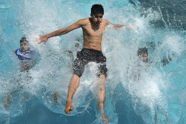 Youths jump into a commercial swimming pool to cool themselves off in Peshawar, Pakistan, Thursday, July 13, 2023. (AP Photo/Muhammad Sajjad)