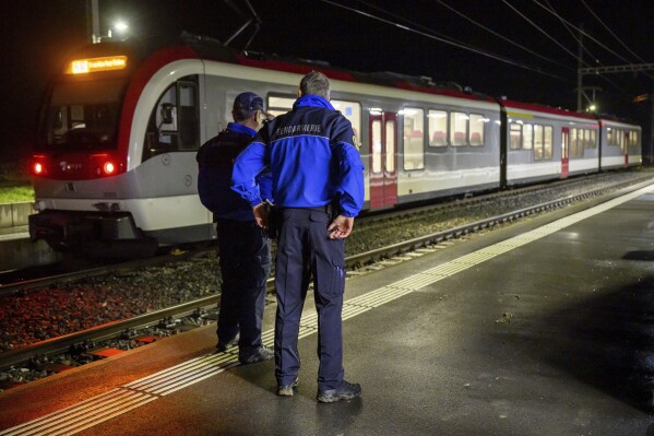 Vaud cantonal police officers watch the Travys train where a hostage-taking incident took place at Essert-sous-Champvent station, Switzerland, Thursday, Feb. 8, 2024. A hostage-taking incident took place on a regional train between Yverdon and Sainte-Croix at around 6: 30 p.m. on Thursday. All hostages were freed and are safe. (Laurent Gillieron/Keystone via AP)