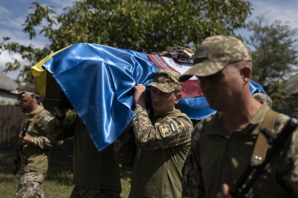 Soldiers carry the coffin with 22-year old Oleksander Mykhailenko's remains in Zhukin, Ukraine, Friday, Aug. 11, 2023. Oleksander, a soldier in the Ukrainian army, died in battle in the Kharkiv region in March this year but his body was only identified recently. (AP Photo/Bram Janssen)