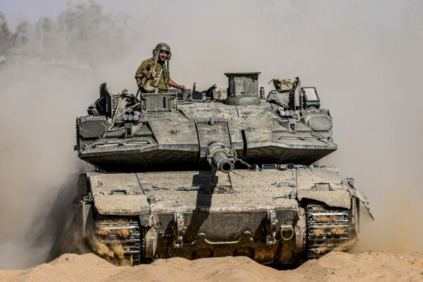 Israeli soldiers drive a tank at a staging ground near the border with the Gaza Strip, in southern Israel, Sunday, May 5, 2024. (AP Photo/Tsafrir Abayov)