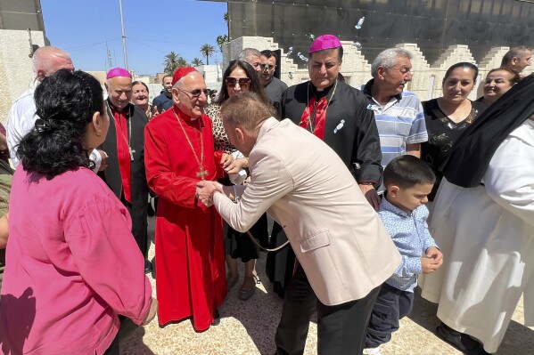 Chaldean Patriarch Louis Sako greets parishioners after a mass following his return from nine months of self-imposed exile in northern Iraq's Kurdish region, in Baghdad, Iraq, Friday April 12, 2024. (AP Photo/Ali Jabar)