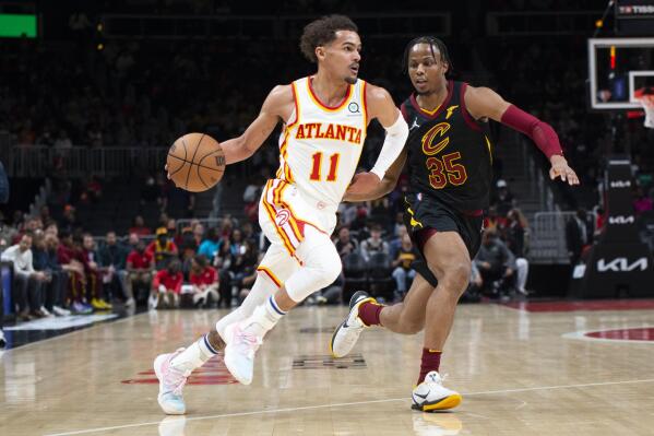 Atlanta Hawks guard Trae Young (11) dribbles past Cleveland Cavaliers forward Isaac Okoro (35) during the first half of an NBA basketball game Thursday, March 31, 2022, in Atlanta. (AP Photo/Hakim Wright Sr.)