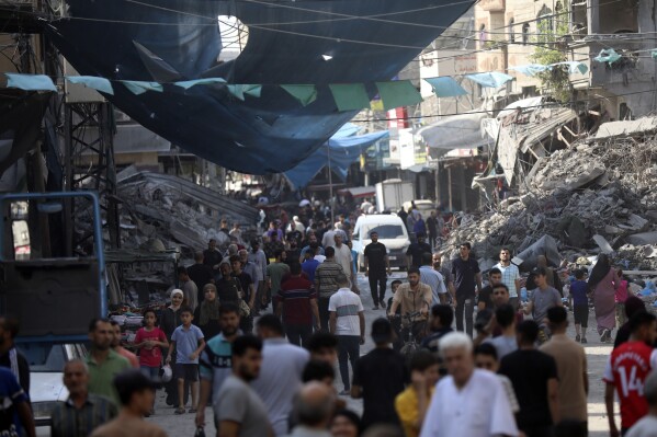 Palestinians walk in the street market of Jabaliya refugee camp, northern Gaza Strip, Wednesday, Nov. 1, 2023, after an Israeli airstrike. (AP Photo/Abed Khaled)