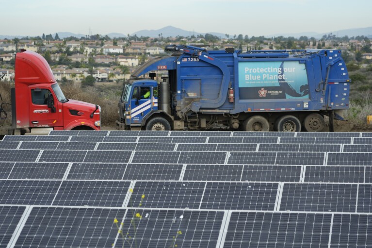 Trash trucks move past solar panels at the Otay Landfill in Chula Vista, Calif., on Friday, Jan. 26, 2024. Two years after California launched an effort to keep organic waste out of landfills, the state is so far behind on getting food recycling programs up and running that it's widely accepted next year's ambitious waste-reduction targets won't be met. (AP Photo/Damian Dovarganes)