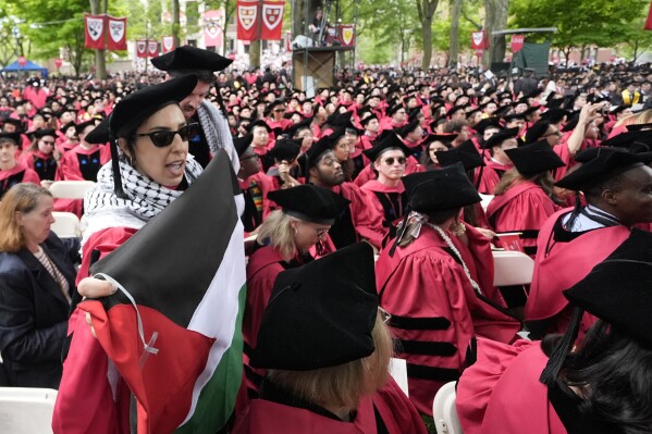 Graduating students chant as they depart commencement in protest to the 13 graduating seniors who were not allowed to participate due to protest activities, in Harvard Yard during commencement at Harvard University, Thursday, May 23, 2024, in Cambridge, Mass. (AP Photo/Charles Krupa)