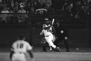 Atlanta Braves' Hank Aaron eyes the flight of the ball after hitting his 715th career homer in a game against the Los Angeles Dodgers in Atlanta, Ga., Monday night, April 8, 1974.  Aaron broke Babe Ruth's record of 714 career home runs.  Dodgers southpaw pitcher  Al Downing, catcher Joe Ferguson and umpire David Davidson look on.  (AP Photo/Harry Harrris)